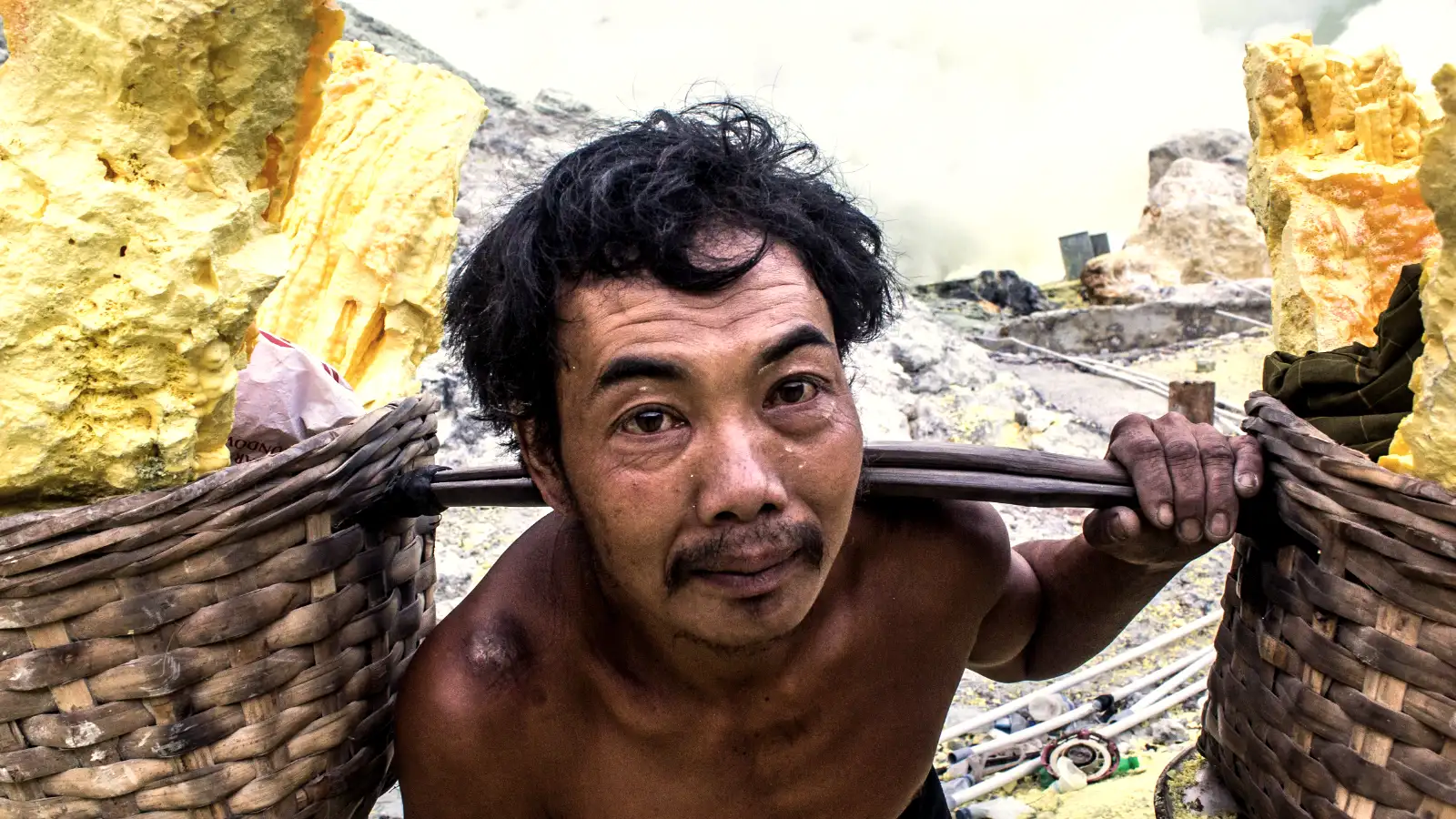 Sulfur miners carrying heavy baskets up the steep slopes of Ijen Crater in East Java