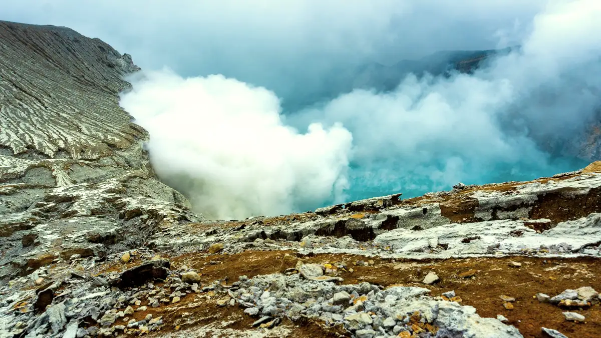 The Majestic Turquoise Lake of Ijen The turquoise acidic lake of Ijen Crater surrounded by steep volcanic walls and rising sulfuric gas